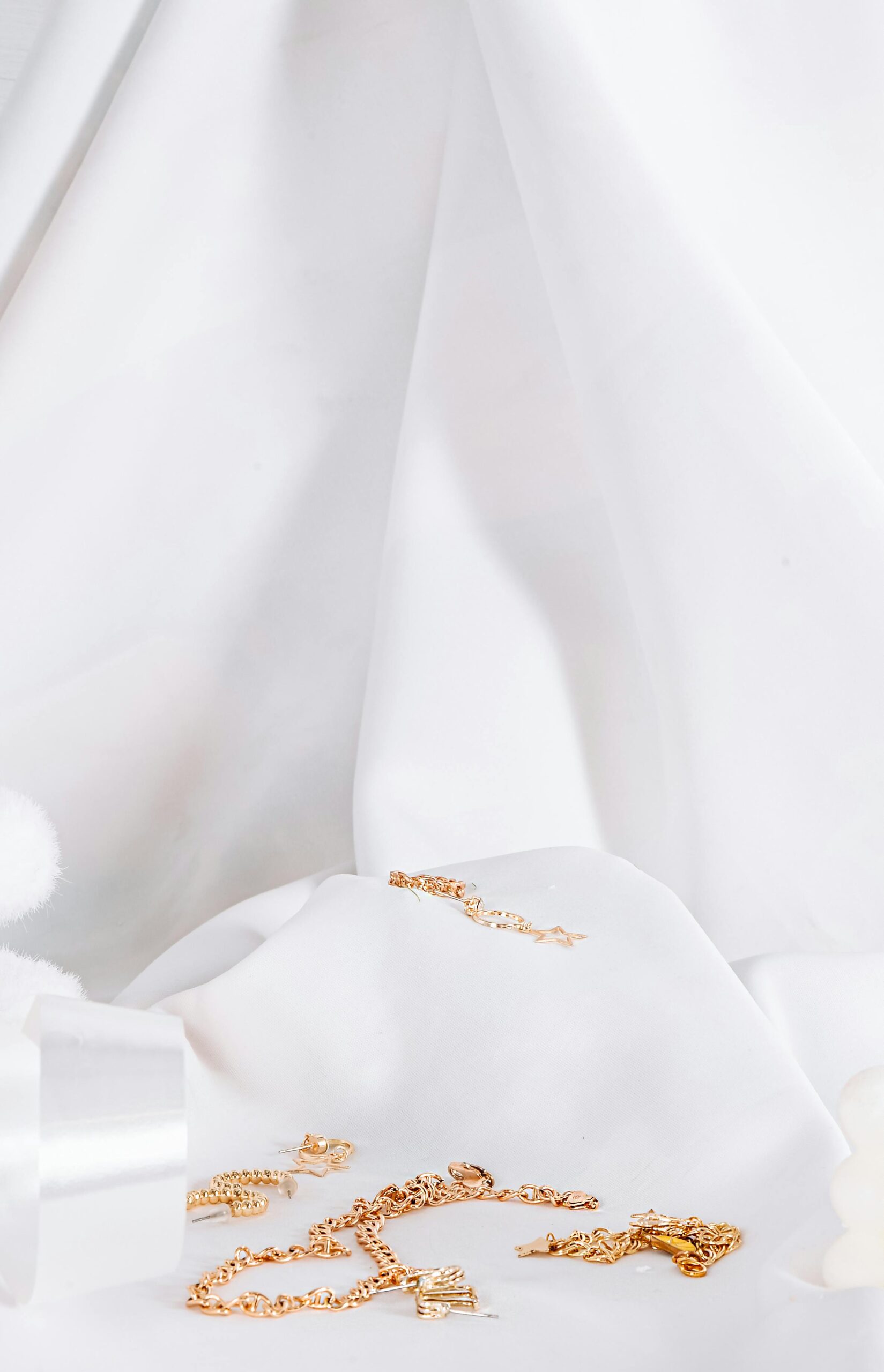 Close-up of gold jewelry elegantly displayed on soft white fabric, creating a luxurious and minimalist aesthetic.